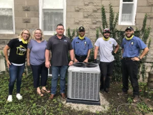 The Top Notch Heating, Cooling & Plumbing team posed in front of a newly-installed AC unit. 