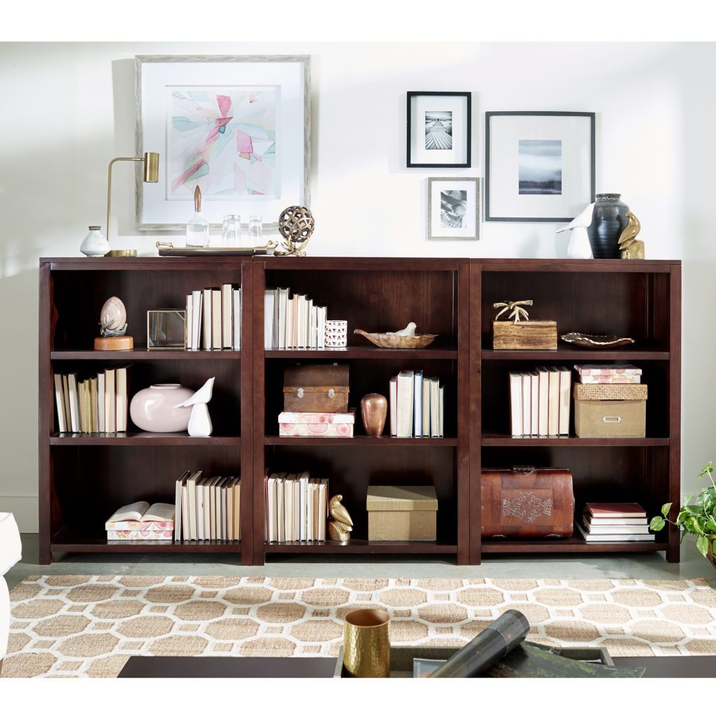A modern living room with bookshelf and gold-accent decor.