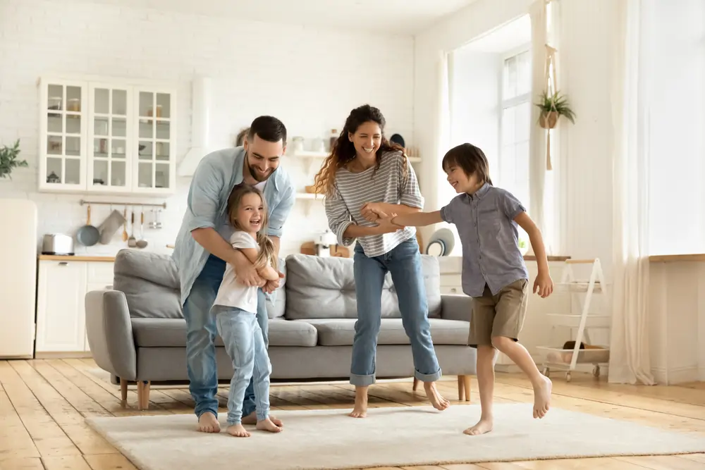 A family of four playing in the living room.