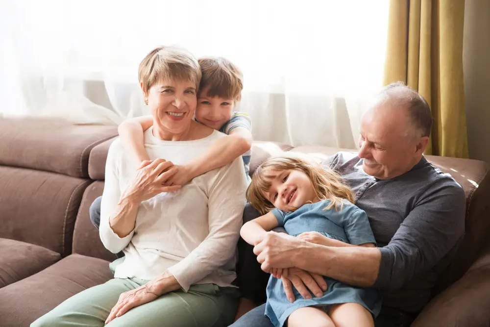 Grandparents on the couch with two children surrounding them.
