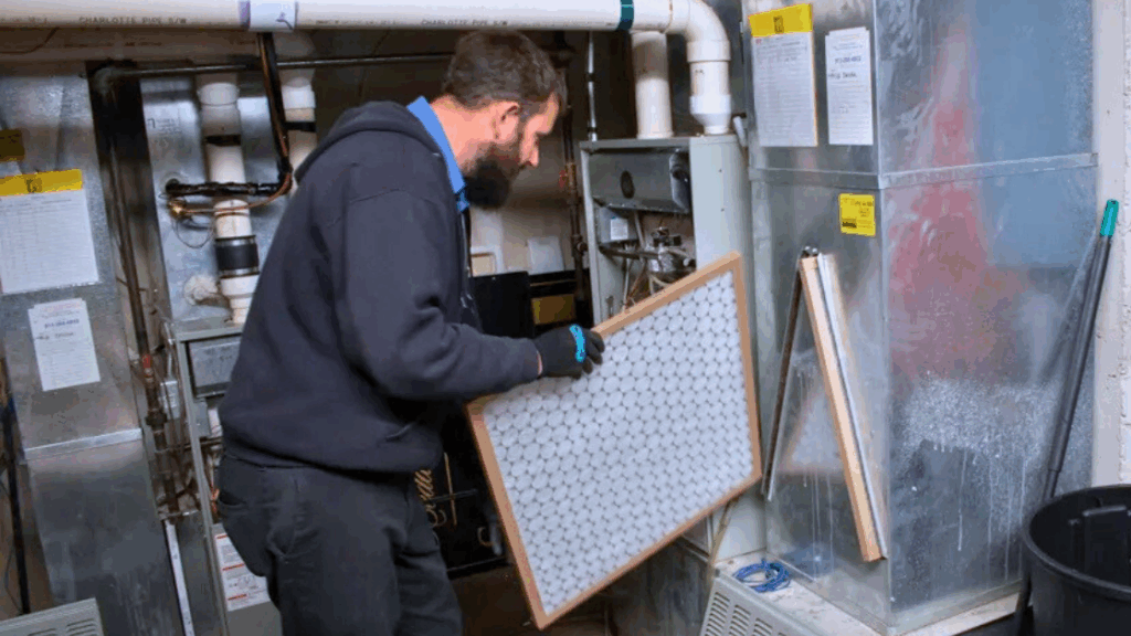 A Top Notch Heating, Cooling & Plumbing technician handling an air filter for a home system.