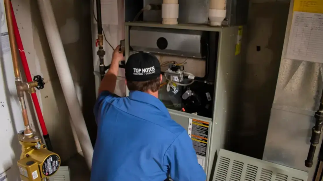 A Top Notch Heating, Cooling & Plumbing technician performing work on a customer's heater.