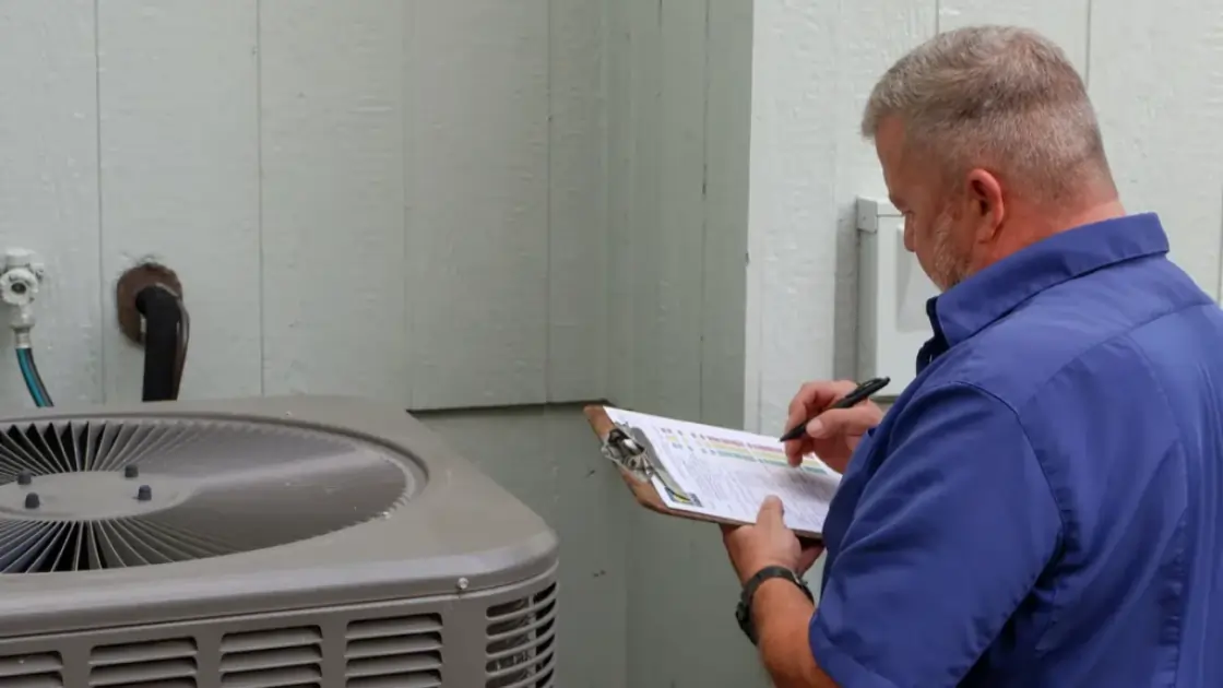  A Top Notch Heating, Cooling & Plumbing technician with clipboard, examining a Kansas City homeowners’ air conditioner. 